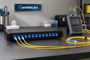 Yellow fiber optic cables connected to a patch panel beside a handheld tester and framed CamNetLink sign
